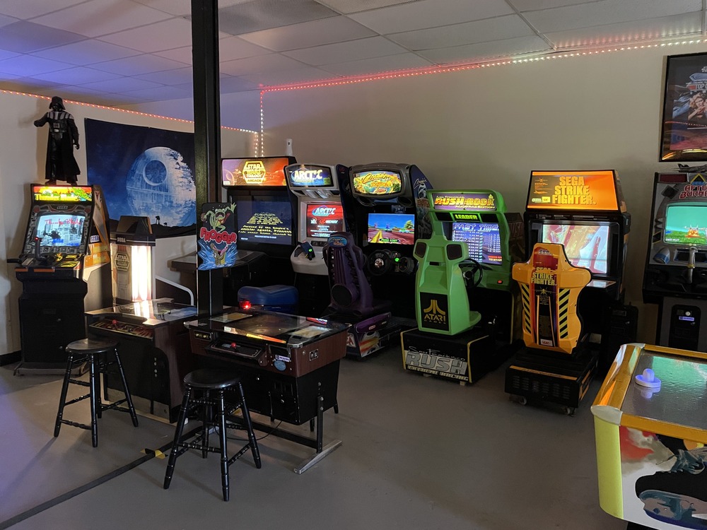 Arcade machines lined up on the back wall, with two table arcade cabinets in front.